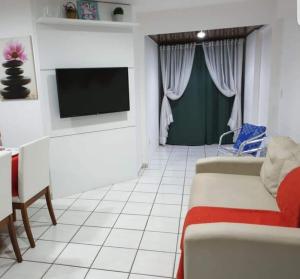Una sala de estar con un sofá y un televisor. en Flat 2 Quartos com vista pro Mar em Hotel 4 Estrelas, en Natal