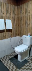 a toilet in a bathroom with a wooden wall at Barn Hills in Ella