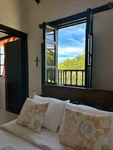 a bed with pillows and a window with a cross at Casa Tirteo ( A 500 m de la plaza principal) in Villa de Leyva