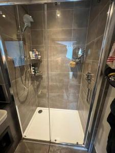 a shower with a glass door in a bathroom at East London's hidden gem - relax after sightseeing in a huge canal view balcony in London