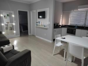 eine Küche und ein Wohnzimmer mit einem weißen Tisch und Stühlen in der Unterkunft Apartamento na Praia da Enseada, 100 mt praia in São Francisco do Sul