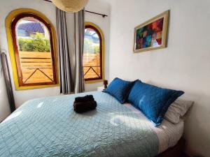 a bedroom with a bed with blue pillows and two windows at Mondrian Santiago in Santiago