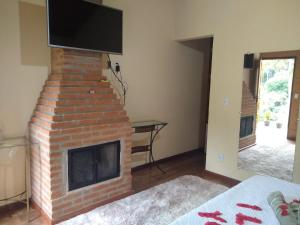 a living room with a brick fireplace with a flat screen tv at All Green Residence in Monte Verde