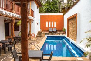a pool with tables and chairs next to a house at Hotel Tierra Roja in Barichara