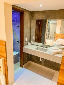 ein Bad mit einem Waschbecken und einem Spiegel in der Unterkunft Villa'l Mare Hotel in Maresias