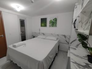若昂佩索阿的住宿－Paradise Beach Flat's，一间白色卧室,配有床和植物