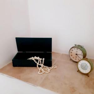 Une boîte noire avec un bouquet de perles près d'une horloge dans l'établissement Casa Borromeo, à Villa Castelli