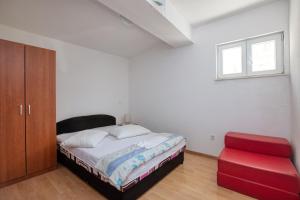 - une chambre avec un lit et un tabouret rouge dans l'établissement Apartments by the sea Stupin Celine, Rogoznica - 21279, à Rogoznica