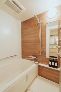 La salle de bains est pourvue d'une baignoire, d'une douche et d'un miroir. dans l'établissement n'estate Kagurazaka, à Tokyo