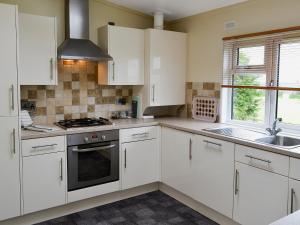 a kitchen with white cabinets and a sink at Apple Blossom in Saint Ervan