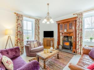 a living room with purple furniture and a fireplace at Colaboll Farmhouse in Lairg