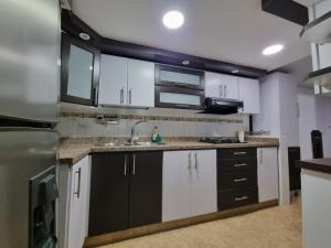 a kitchen with black and white cabinets and a sink at Hospedaje Casa Leví in Cali