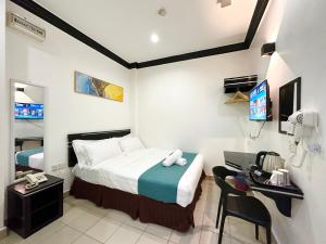 ein Hotelzimmer mit einem Bett, einem Schreibtisch und einem TV in der Unterkunft Hotel Tourist City Centre by HotSpot Essential in Kota Kinabalu