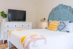 um quarto com uma cama branca, uma cabeceira azul e uma televisão. em Folly Fantasea em Folly Beach