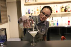 een vrouw die een drankje in een martini glas giet bij Ski Rider Hotel in Perisher Valley