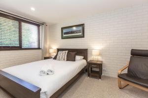 a bedroom with a large bed and a chair at Lake Pines 2 of 24 Cobbon Crescent Free WiFi and Stay 7 nights only pay 6 in Jindabyne