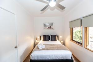Un dormitorio con una cama y un ventilador de techo. en Montebello 3 12 Cobbodah Street, en Jindabyne