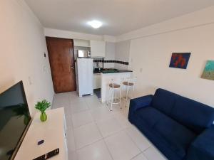a living room with a blue couch and a kitchen at Vela e Mar in João Pessoa