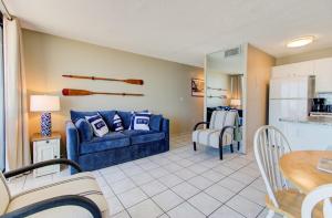 a living room with a blue couch and a kitchen at 0610 Smooth Sailing by Atlantic Towers in Carolina Beach