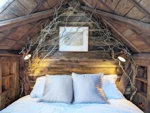 a bedroom with a bed with branches on the ceiling at Holme Street House and Dove Cote Lodge in Pulborough