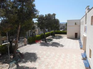 un patio con bancos y árboles junto a un edificio en Sacro Cuore Opera Don Guanella en Torre Canne