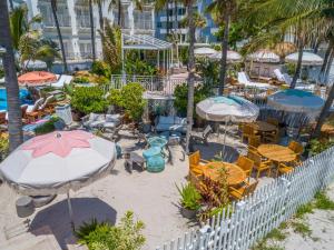 um pátio exterior com mesas, cadeiras e guarda-sóis em The Savoy Hotel & Beach Club em Miami Beach
