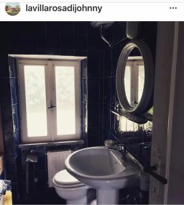 een badkamer met een wastafel, een toilet en een spiegel bij La Villa Rosa di Johnny in Ronciglione