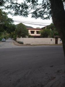 an empty street with a white wall and a house at Casa em Itaipu in Niterói