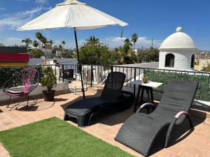 a patio with two chairs and a table and an umbrella at Sofia Hostel Cabo in Cabo San Lucas