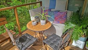 Deluxe Studio with Forest Views, Noosa Hinterland في Doonan: فناء على طاولة وكراسي على شرفة