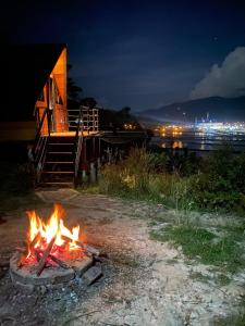 un fuego arde frente a una cabaña por la noche en Glamping refugio Gaia, en Paipa