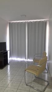 un soggiorno con 2 sedie e una TV di Quarto em Apto ao lado Shopping a Cuiabá