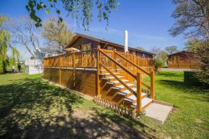 a large wooden house with a large deck at Stunning Lodge With Free Wifi For Hire At Carlton Meres In Suffolk Ref 60013m in Saxmundham