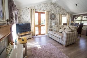 sala de estar con sofá y TV en Stunning Lodge With Free Wifi For Hire At Carlton Meres In Suffolk Ref 60013m en Saxmundham