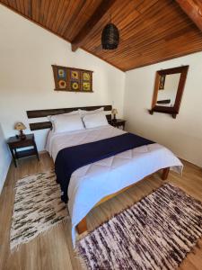 a bedroom with a large bed and a rug at Chalés Monte Verde in Monte Verde