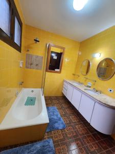 Baño amarillo con bañera y 2 lavabos en Chalés Monte Verde, en Monte Verde