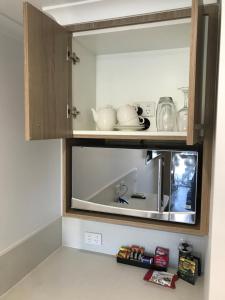 a kitchen with a cupboard with some dishes in it at Room Motel Kingaroy East in Kingaroy