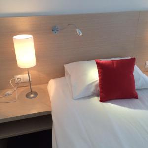 a bedroom with a bed with a red pillow and a lamp at Loft Hotel in Tula