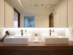 a bathroom with two sinks and a mirror at WeBase KAMAKURA in Kamakura