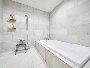 a white bathroom with a tub and a sink at WeBase KAMAKURA in Kamakura