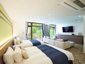 a hotel room with three beds and a tv at WeBase KAMAKURA in Kamakura