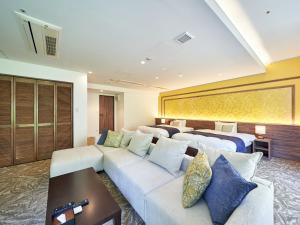 a hotel room with two beds and a couch at WeBase KAMAKURA in Kamakura