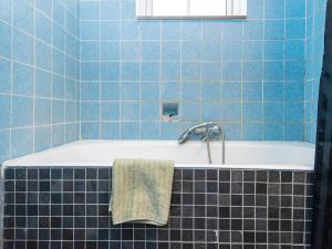 W wyłożonej niebieskimi kafelkami łazience znajduje się wanna z ręcznikiem. w obiekcie Holiday home Nordborg XXV w mieście Nordborg