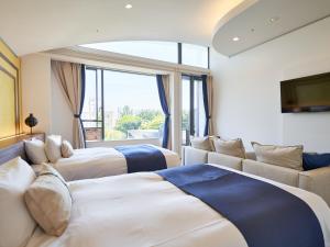a hotel room with three beds and a couch at WeBase KAMAKURA in Kamakura