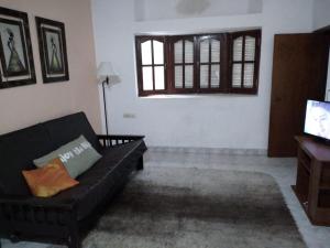 uma sala de estar com um sofá preto e uma televisão em Departamento Familiar Amplio y cómodo em Santiago del Estero