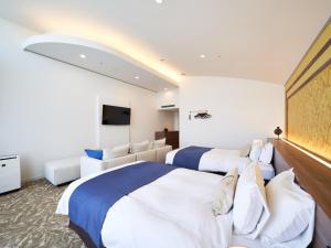 a hotel room with two beds and a flat screen tv at WeBase KAMAKURA in Kamakura