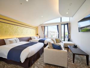 a hotel room with two beds and a couch at WeBase KAMAKURA in Kamakura