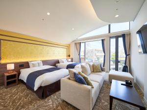 a hotel room with two beds and a couch at WeBase KAMAKURA in Kamakura