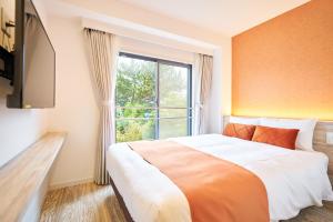 a bedroom with a large bed and a window at WeBase KAMAKURA in Kamakura