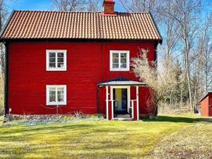 a red house with a red roof on a field at Holiday home Vingåker III in Vingåker